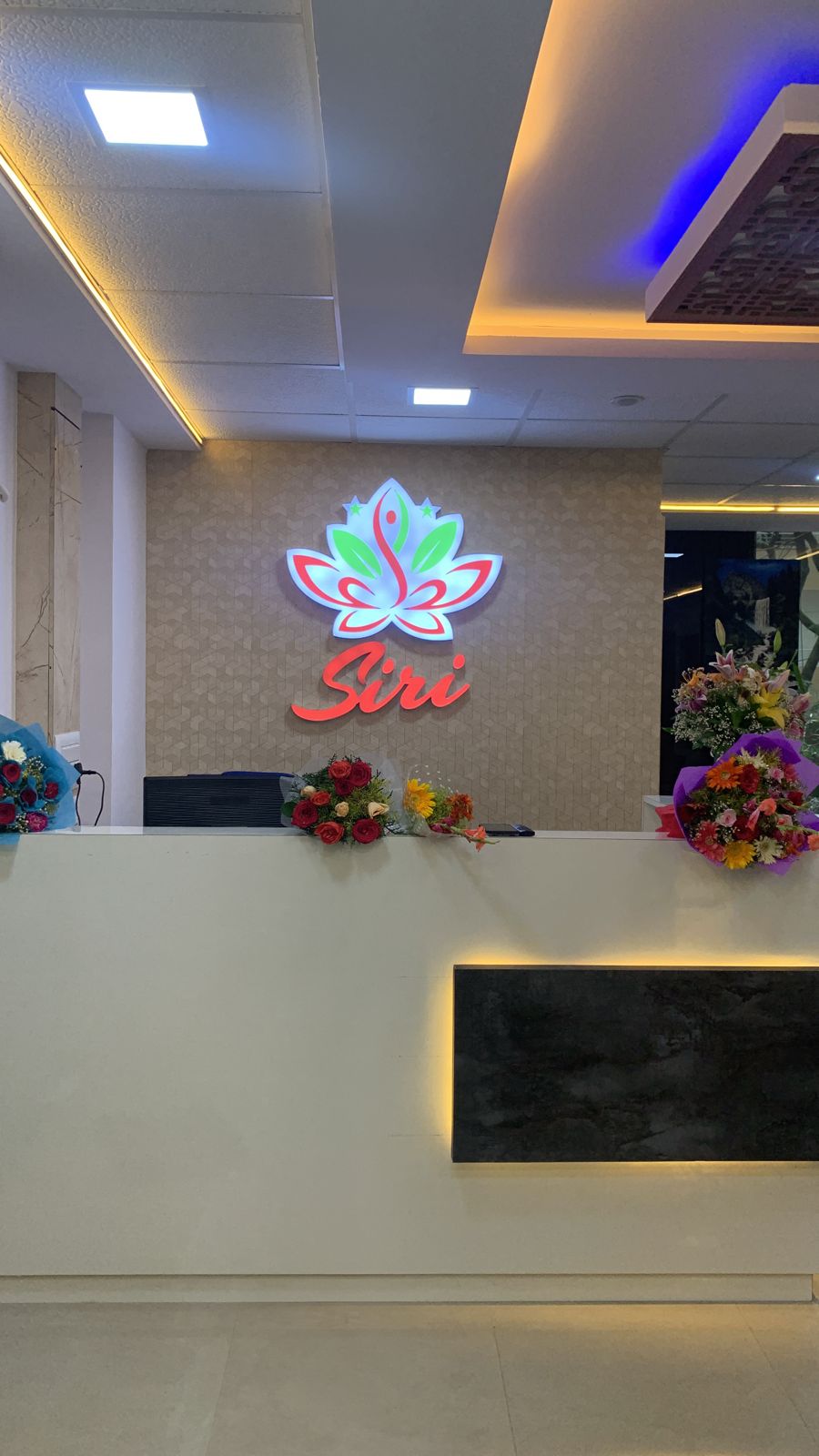 Close-up of reception desk with illuminated Siri logo and fresh flowers